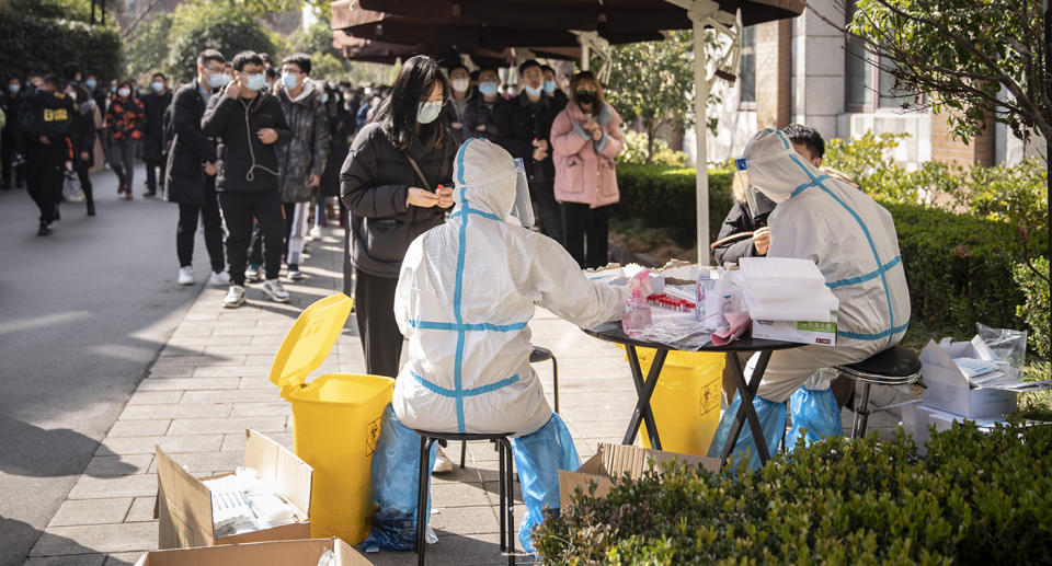 People stand in line as medical workers wearing personal protective equipment (PPE) prepare to collect swab samples at a Covid-19 testing center in Shanghai, China, on Saturday, Feb. 6, 2021. China remains on high alert and have discouraged travel during the Lunar New Year holiday that starts Feb. 11. Photographer: Qilai Shen/Bloomberg via Getty Images