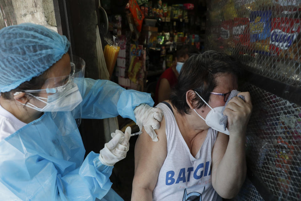 A woman reacts as a health worker inoculates her with China's Sinovac COVID-19 vaccine outside their store in Manila, Philippines on Wednesday, May 19, 2021. Philippine President Rodrigo Duterte has eased a lockdown in the bustling capital and adjacent provinces to fight economic recession and hunger but has still barred public gatherings this month, when many Roman Catholic festivals are held. (AP Photo/Aaron Favila)