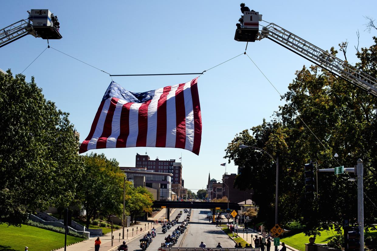 Motorcycle riders make their way past a giant U.S. flag suspended between two ladder trucks on Second Street during the Ride To Remember 9-11 Annual Memorial Parade & Ceremony Sunday, Sept. 10, 2017. [Ted Schurter/The State Journal-Register]