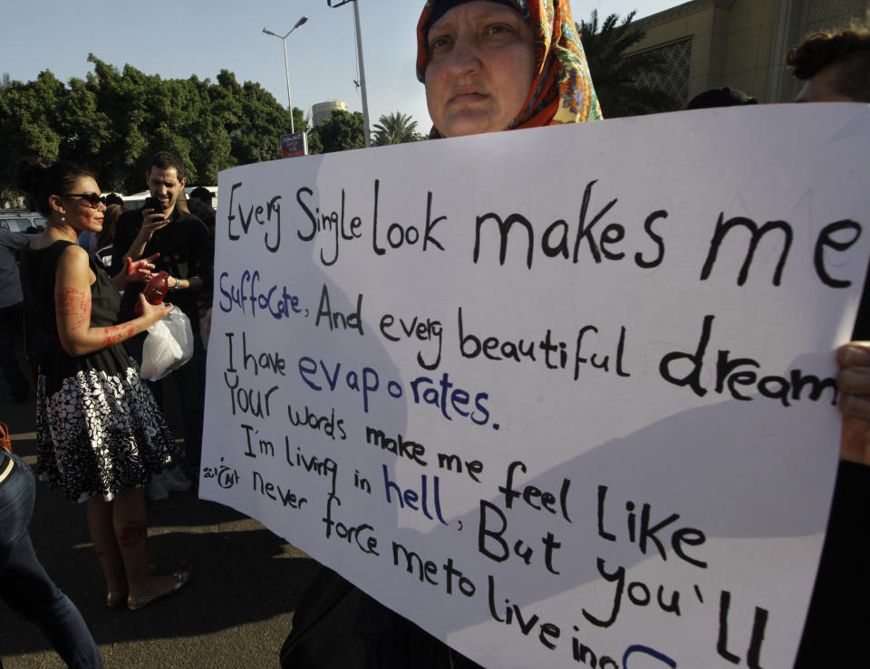 FILE - In this June 14, 2014 file photo, an Egyptian woman holds a banner during a protest against sexual harassment in Cairo, Egypt. A video posted on Facebook Aug. 15, 2018, by an Egyptian woman who says a man stalked her at a bus stop has stirred online debate, with many -- including women -- taking the man’s side. Some say he was politely flirting and the woman overreacted, while others have speculated about what she was wearing, suggesting she was the one at fault. The diverging responses point to the difficulty in combatting the rampant sexual harassment on Egypt’s streets. (AP Photo/Amr Nabil, File)