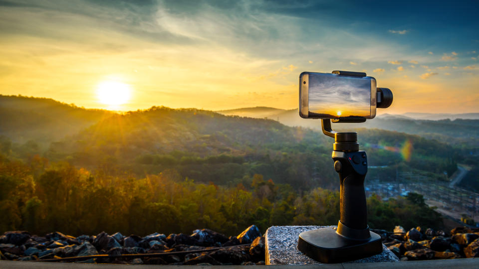 A smartphone being used to take a picture of a sunset.