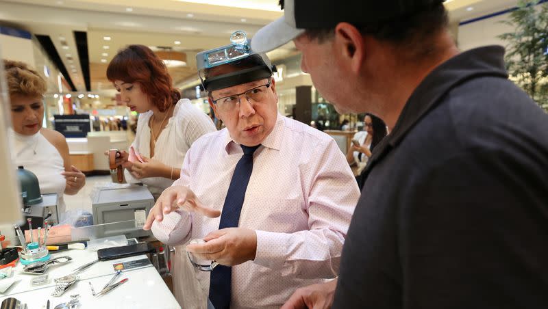 Marcelo Sandivar, certified watch technician and owner of Fashion Watch & Clock, helps a customer at the company’s kiosk in Fashion Place Mall in Murray on Thursday, Aug. 24, 2023. His wife and granddaughter work behind him.