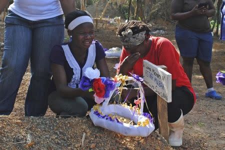 Women weep at the grave of lost relative Esther Mulbah at a cemetery for victims of Ebola virus in Suakoko, Liberia, March 11, 2015. REUTERS/James Giahyue