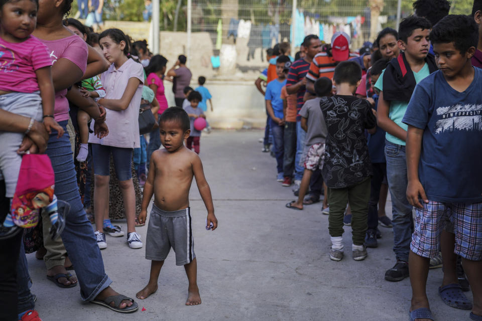 In this Aug. 30, 2019, photo, migrants, many who were returned to Mexico under the Trump administration’s “Remain in Mexico” program, wait in line to get a meal in an encampment near the Gateway International Bridge in Matamoros, Mexico. The program, officially called the Migrant Protection Protocols, was instituted by the U.S. and Mexico as a way of deterring migrants from crossing the border to seek asylum. (AP Photo/Veronica G. Cardenas)