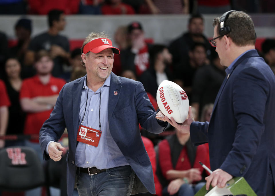 FILE - In this Jan. 2, 2019, file photo, Dana Holgorsen, the newly named football coach for the Houston college football team, gets autographed footballs to toss to the crowd as he is recognized during halftime of an NCAA college basketball game between Tulsa and Houston, in Houston. (AP Photo/Michael Wyke, File)