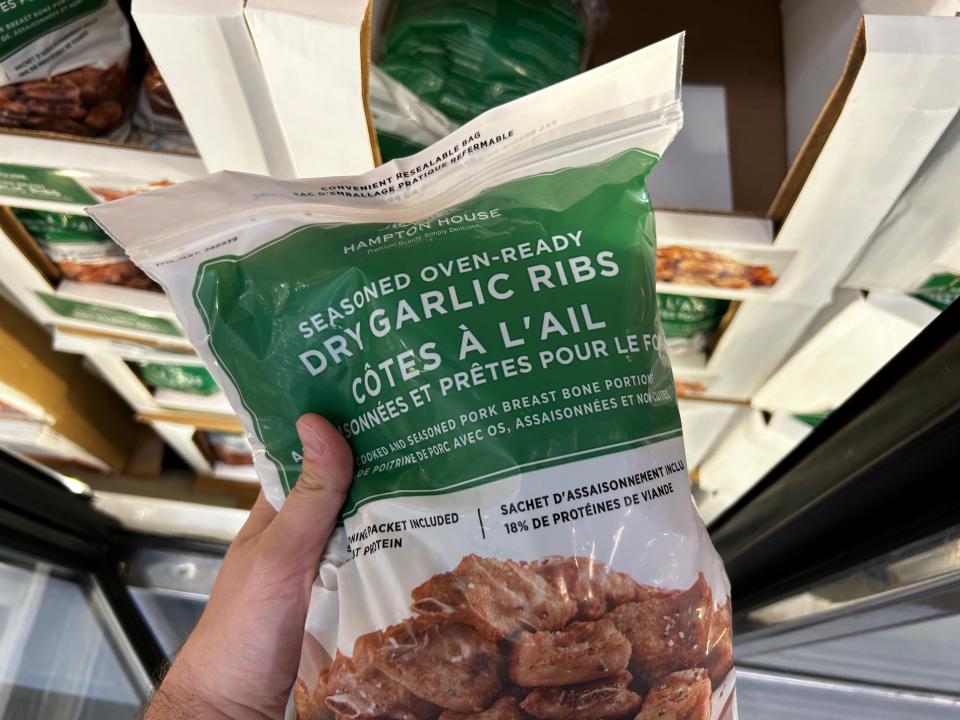 Mackenzie holding a bag of seasoned oven-ready dry-garlic ribs from Costco.