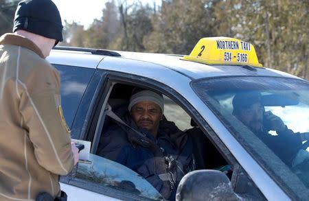 A Northern Taxi driver watches as his fare, a family who claimed to be from Sudan, has his passport and visa checked by a U.S. border patrol agent near the U.S.-Canada border in Champlain, New York, U.S., February 17, 2017. REUTERS/Christinne Muschi/Files