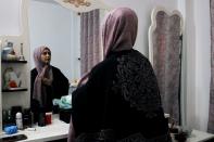 Jassem, 24, an Iraqi nurse arranges her scarf in front of a mirror at home in Baghdad