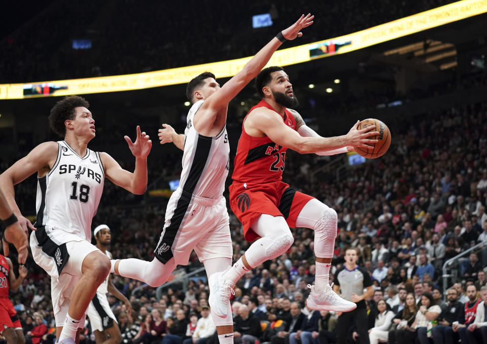 Fred VanVleet, de los Raptors de Toronto, dispara delante de Isaiah Roby (18) y Doug McDermott, de los Spurs de San Antonio, en el encuentro del miércoles 8 de febrero de 2023 (Arlyn McAdorey/The Canadian Press via AP)