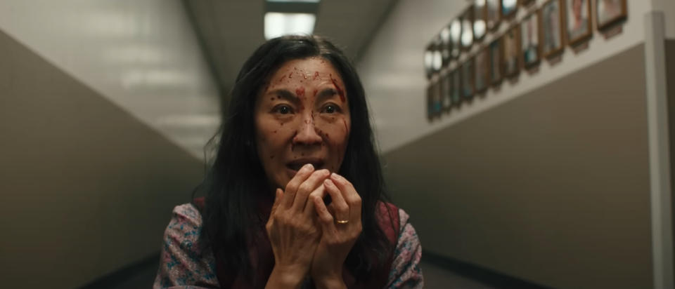 Michelle Yeoh as Evelyn Wang looks distressed in a hallway with photos on the wall.