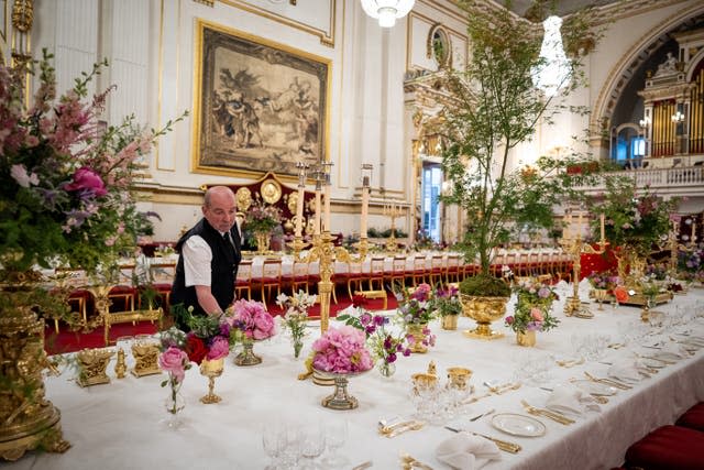 The finishing touches being applied to the tables in the Ballroom of Buckingham Palace before the state banquet 