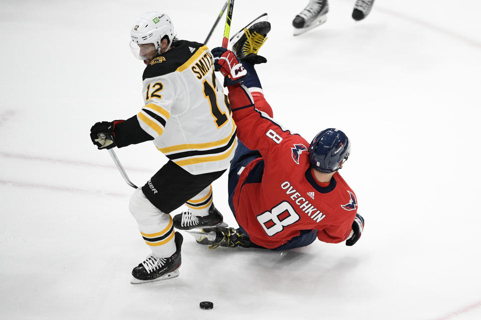 Washington Capitals left wing Alex Ovechkin (8) gets tripped up by Boston Bruins center Craig Smith (12) during the first period in Game 5 of an NHL hockey Stanley Cup first-round playoff series, Sunday, May 23, 2021, in Washington. (AP Photo/Nick Wass)