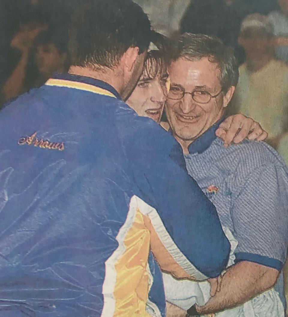 Dan Olson (center) of Watertown celebrates with his father and Arrow assistant coach Steve (right), as well as head coach Bob Hirsch (left), after he won the 130-pound title in the 2004 state Class A wrestling tournament in Aberdeen. Dan Olson, a two-time state runner-up, won to complete a 39-0 season.