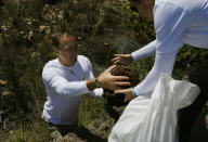 Les Ansley collects fresh elephant dung in the Botlierskop Private Game Reserve, near Mossel Bay, South Africa, Tuesday, Oct. 24, 2019. The makers of a South African gin infused with elephant dung swear their use of the animal’s excrement is no gimmick. The creators of Indlovu Gin, Les and Paula Ansley, stumbled across the idea a year ago after learning that elephants eat a variety of fruits and flowers and yet digest less than a third of it. (AP Photo/Denis Farrell)