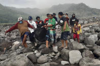 Rescuers and villagers carry a body bag containing the remains of a victim in the eruption of Mount Semeru, in Candi Puro village, Lumajang, East Java, Indonesia, Tuesday, Dec. 7, 2021. Indonesia's president on Tuesday visited areas devastated by a powerful volcanic eruption that killed a number of people and left thousands homeless, and vowed that communities would be quickly rebuilt. (AP Photo/Rokhmad)