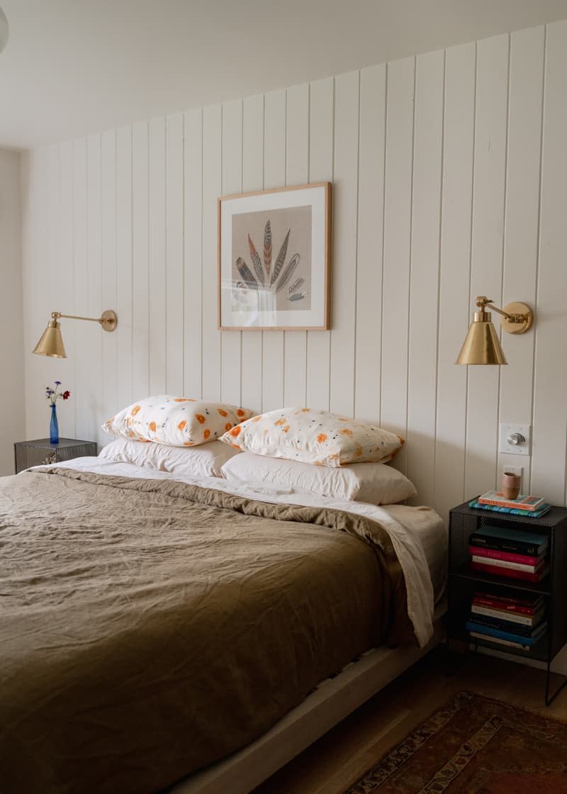 Feather print artwork mounted above neatly made bed.