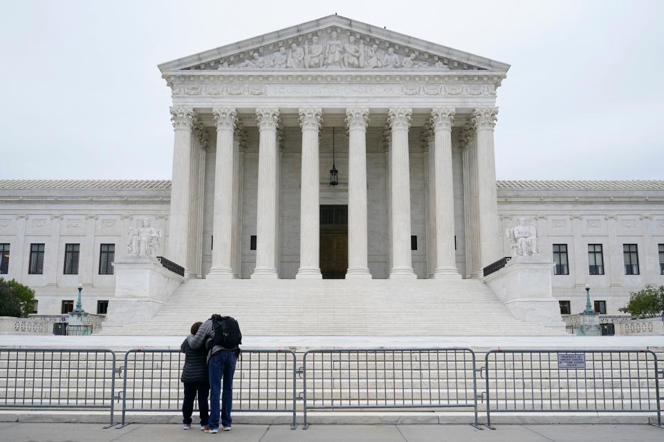 A woman and man pray outside the Supreme Court on Capitol Hill in Washington, D.C., on Oct. 27, 2020, a day after the Senate confirmed Amy Coney Barrett to become a Supreme Court justice.