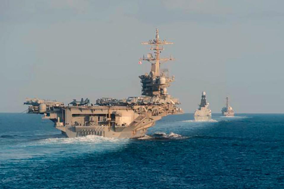 The aircraft carrier USS Abraham Lincoln, left, the air-defense destroyer HMS Defender and the guided-missile destroyer USS Farragut transit the Strait of Hormuz with the guided-missile cruiser USS Leyte Gulf.