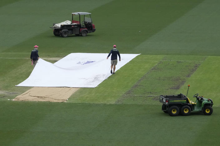 Grounds crew members prepare the wicket after a rain delay during the first day of the cricket test match between South Africa and Australia at the Sydney Cricket Ground in Sydney, Wednesday, Jan. 4, 2023. (AP Photo/Rick Rycroft)