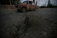 A car drives past the remains of spent ammunition following a recent shelling in Tartar