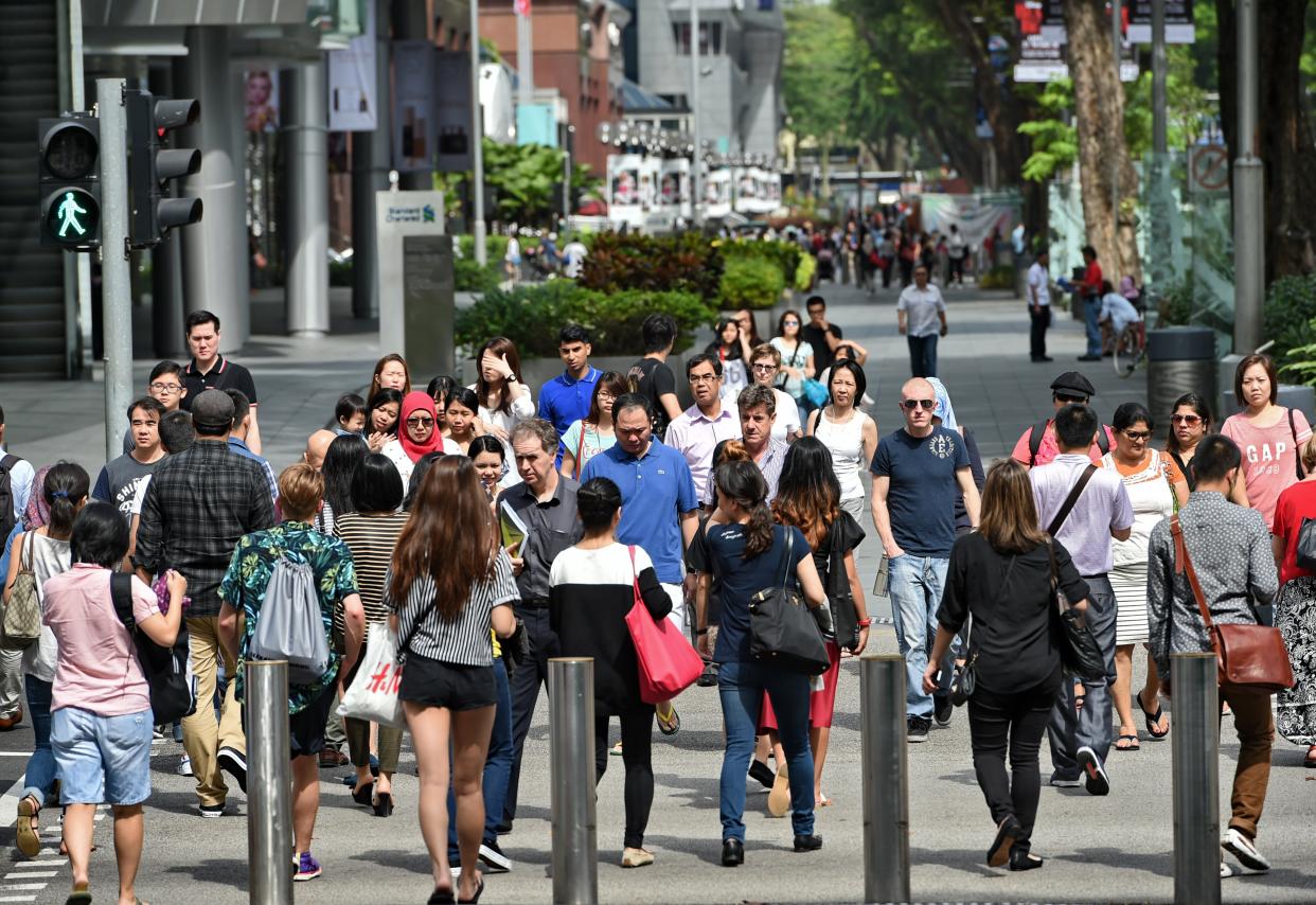 Pedestrians cross a street at the Orchard Road shopping district in Singapore  on March 12, 2015. AFP PHOTO / ROSLAN RAHMAN        (Photo credit should read ROSLAN RAHMAN/AFP via Getty Images)