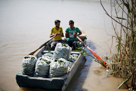 Iraqis men transport goods across the Tigris by boat as flooding after days of rainfall has closed the city's bridges, at the village of Thibaniya, south of Mosul, Iraq April 16, 2017. REUTERS/Muhammad Hamed