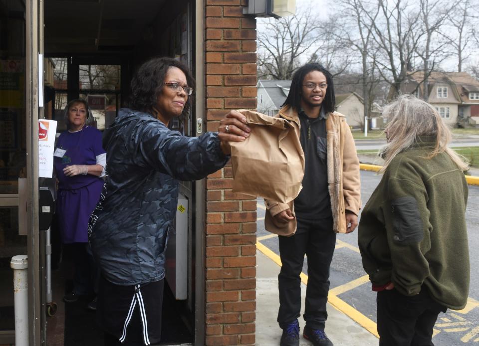 Center of Hope program manager Lajoyce Harris hands a full lunch bag to a client waiting outside in December 2020.