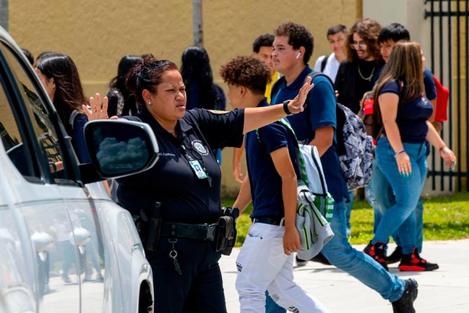 La agente de policía de la Ciudad de Miami C. González ayuda a los estudiantes que salen de la preparatoria Miami a cruzar la calle al final del primer día de clases en Miami, Florida, el miércoles 17 de agosto de 2022.