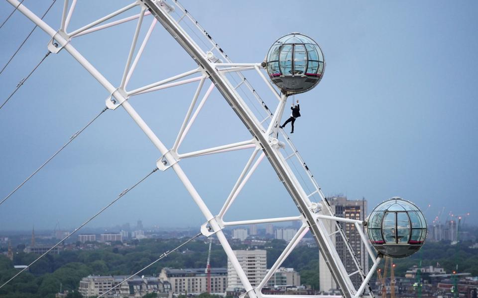 A man dressed as James Bond hangs from a pod on the London Eye ahead of the world premiere of No Time To Die