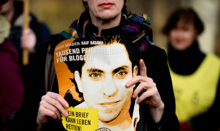 An Amnesty International activist brandishes a picture of Saudi blogger Raif Badawi during a protest staged January 29, 2015, at Saudi Arabia's embassy in Berlin against his flogging punishment