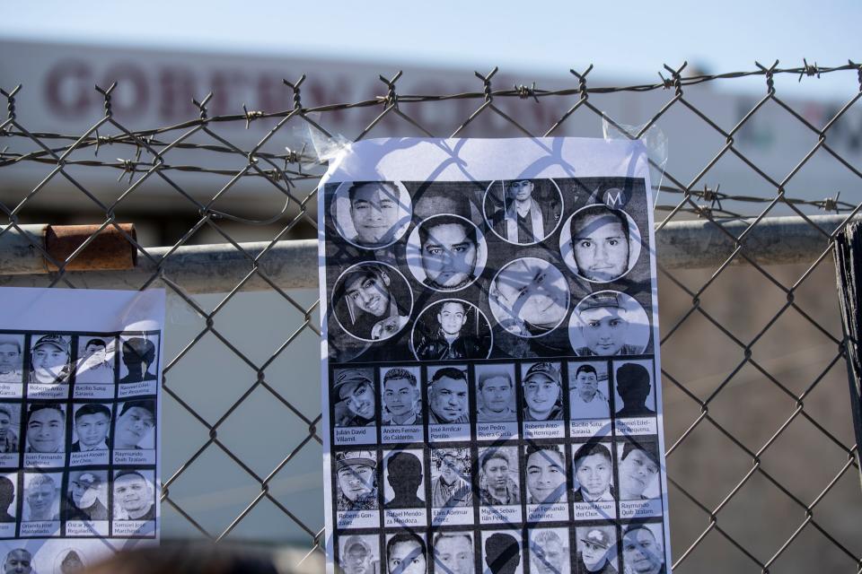 Carlos Mayorga, director of Colectivo Angeles Mensajeros, places signs with the photos and names of the 40 migrants in front of the Mexican migrant detention center where the migrants on the anniversary of the tragic incident in Ciudad Juárez.