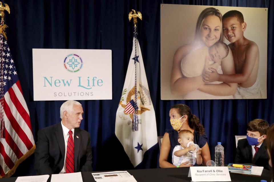 Vice President Mike Pence, left, speaks with Kia Farrell with her sons Ollie Farrell-Kalajainnen, 11-months-old, and Ocean Farrell-Lindsey, 11, during a stop at A Woman's Place Medical Clinic in Pinellas Park, Fla., on Wednesday Aug. 5, 2020, where he discussed pro life options with staffers and patrons. Farrell said she would have likely aborted Ollie if she had not received counseling through the clinic, which provides pregnancy testing, sonograms, well woman care, counseling, life skills training and health education at four locations in Pinellas and Hillsborough counties. (Douglas R. Clifford/Tampa Bay Times via AP)