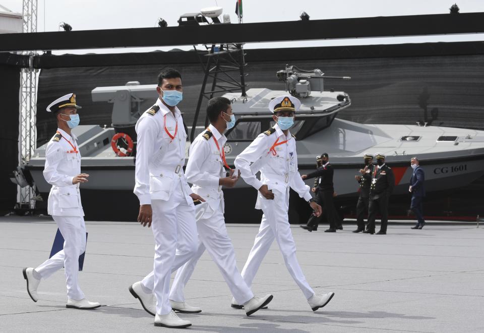 Navy officers walk past a combat boat built by Alfattan in the UAE, on the opening day of the regions leading naval defence and maritime security event, NAVDEX, in Abu Dhabi, United Arab Emirates, Sunday, Feb. 21, 2021. (AP Photo/Kamran Jebreili)