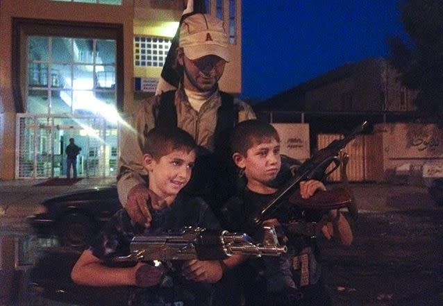 An Islamic militant group fighter stands with two children posing with weapons. Photo: AP/file