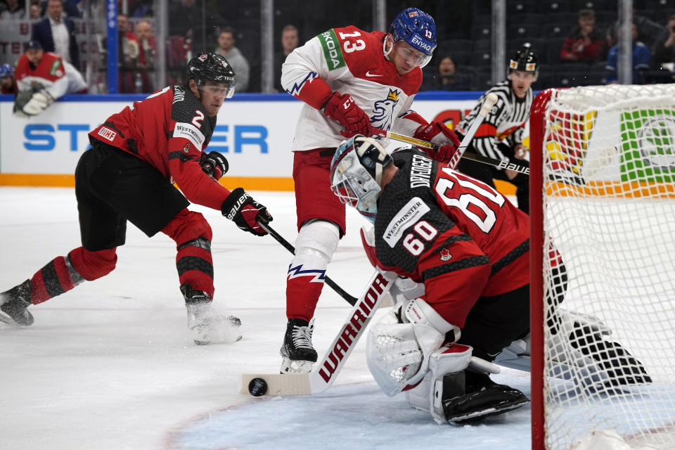 Canada's Chris Driedger deflects the puck as Jakub Vrana of the Czech Republic looks on during a match between the Czech Republic and Canada in the semifinals of the Hockey World Championships, in Tampere, Finland, Saturday, May 28, 2022. (AP Photo/Martin Meissner)
