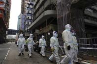 Cleaners wearing protective suits, gather in the Yau Ma Tei area, in Hong Kong, Saturday, Jan. 23, 2021. Thousands of Hong Kong residents were locked down Saturday in an unprecedented move to contain a worsening outbreak in the city, authorities said. (AP Photo/Vincent Yu)