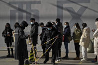 CORRECTS TO SWAB, NOT NASAL SWAB - Security guards set up the barricade line as people line up to get a swab for the COVID-19 test to meet traveling requirements at a mobile coronavirus testing facility outside a commercial office buildings in Beijing, Sunday, Jan. 16, 2022. Beijing has reported its first local omicron infection, according to state media, weeks before the Winter Olympic Games are due to start. (AP Photo/Andy Wong)