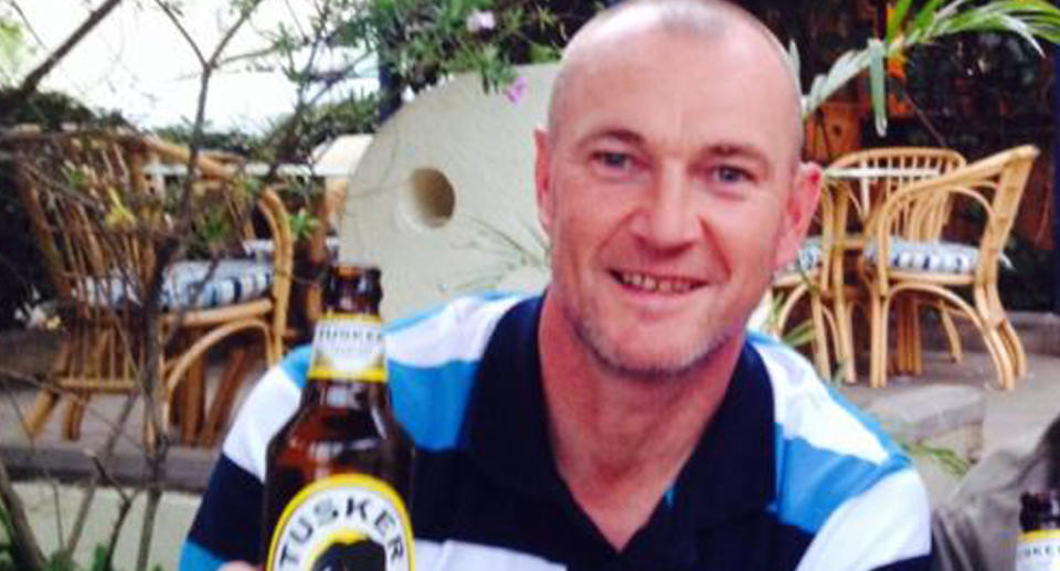 Malcolm Callender sits in a bar holding a beer. 