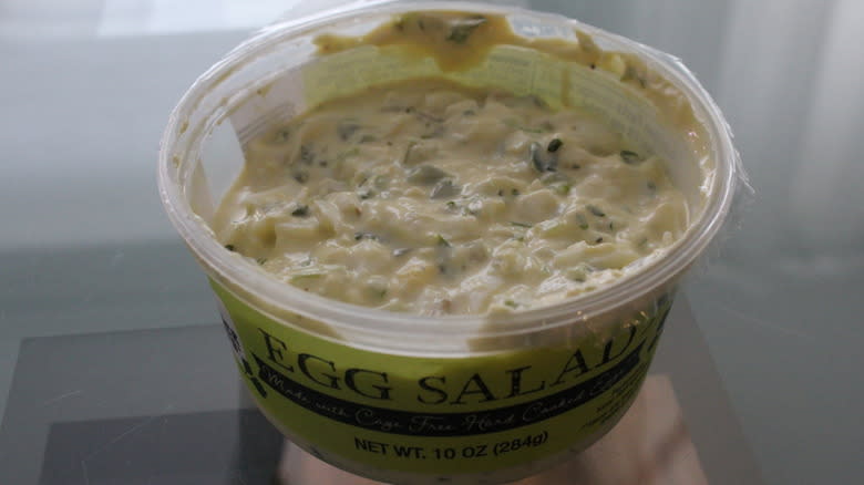 Container of egg salad with herbs and green label