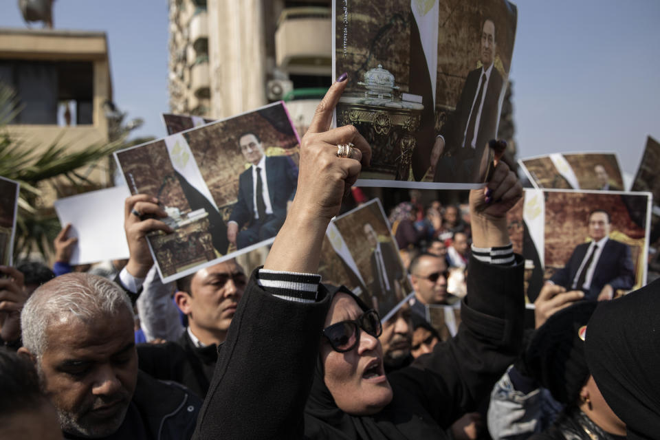 Supporters of ousted President Hosni Mubarak hold posters with his photograph near the cemetery where he will be buried, in the Heliopolis neighborhood of Cairo, Egypt, Wednesday, Feb. 26, 2020. Egypt is holding a full-honors military funeral for Mubarak who was ousted from power in the 2011 Arab Spring uprising. Mubarak, 91, died Tuesday at a Cairo military hospital from heart and kidney complications. (AP Photo/Nariman El-Mofty)