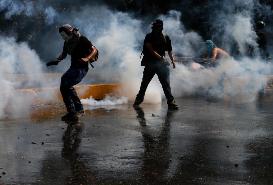 Manifestantes patean bombas de gases lacrimógenas para devolverlas hacia los agentes antimontines en una protesta antigubernamental en Caracas, Venezuela, el miércoles 12 de marzo de 2014. (AP Photo/Fernando Llano)