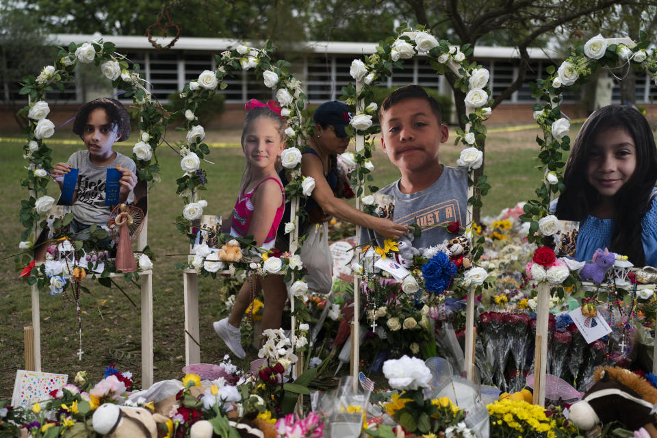 Cat Perez, 39, lays flowers at a memorial at Robb Elementary School in Uvalde, Texas Monday, May 30, 2022, to honor the victims killed in last week's school shooting. Photographs of the victims, from left, show Layla Salazar, McKenna Lee Elrod, Jayce Carmelo Luevanos and Nevaeh Alyssa Bravo. (AP Photo/Jae C. Hong)