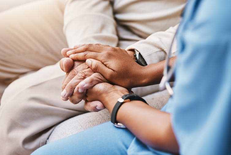 Close up of a care worker holding the hands of a woman.