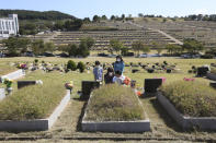 Family members wearing face masks pay respects to their ancestral cemetery ahead of Chuseok holiday, the Korean version of Thanksgiving Day, at a cemetery in Paju, South Korea, Sunday, Sept. 27, 2020. South Korea's national cemeteries will be closed during the upcoming Chuseok holiday during the five-day holidays from Sept. 30 to Oct. 4 to prevent the spread of the coronavirus.(AP Photo/Ahn Young-joon)