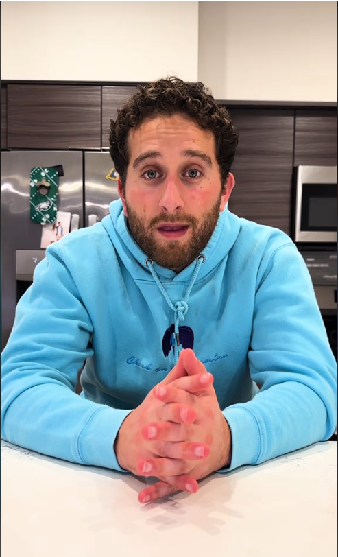 Man in a casual hoodie sitting at a kitchen counter