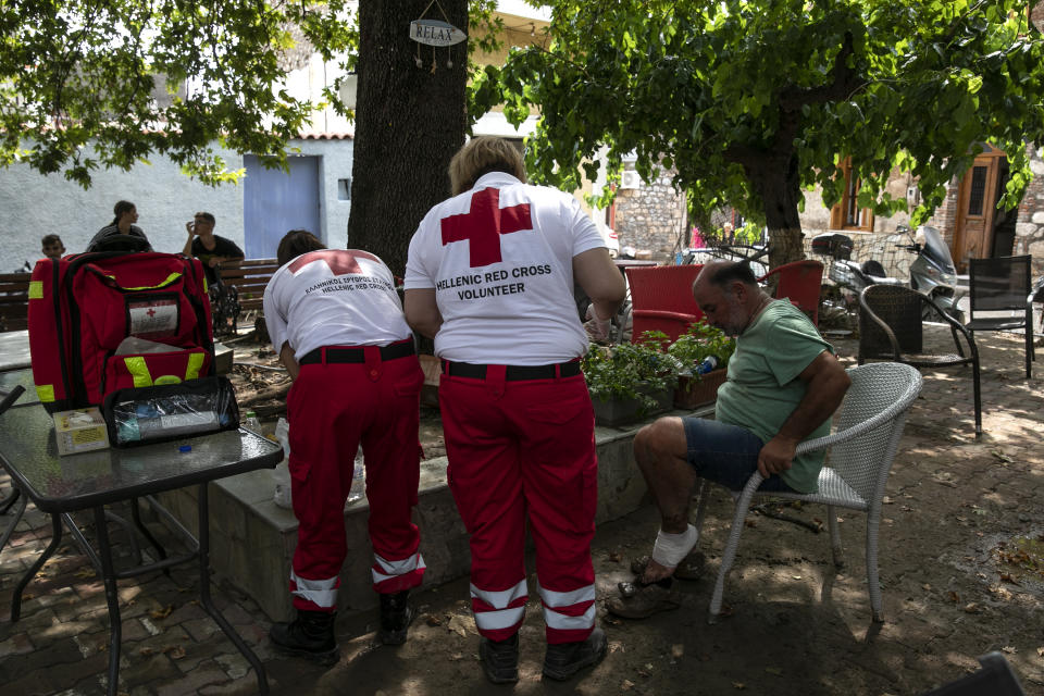 Members of Red Cross treat a wounded man following a storm at the village of Politika, on Evia island, northeast of Athens, on Sunday, Aug. 9, 2020. Five people have been found dead and dozens have been trapped in their homes and cars from a storm that has hit the island of Evia, in central Greece, police say. (AP Photo/Yorgos Karahalis)