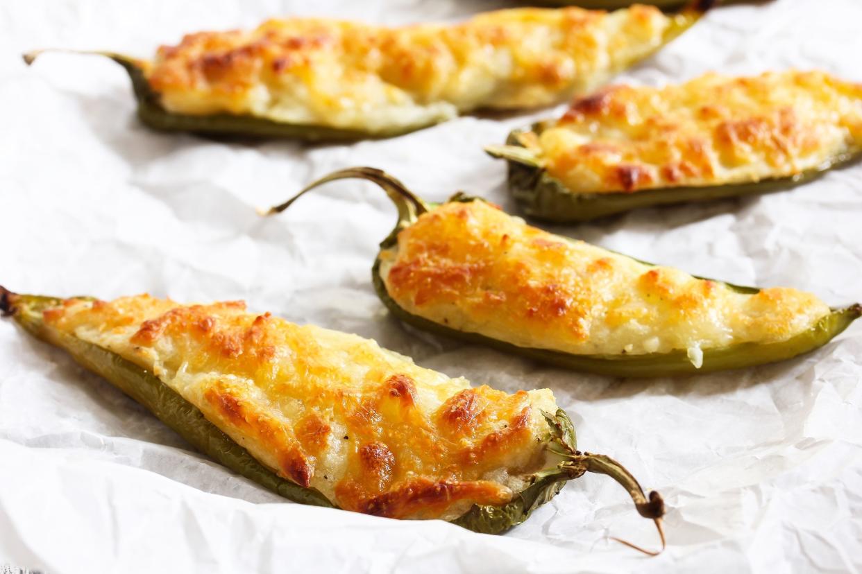 Four black bean and corn stuffed jalapenos on white paper