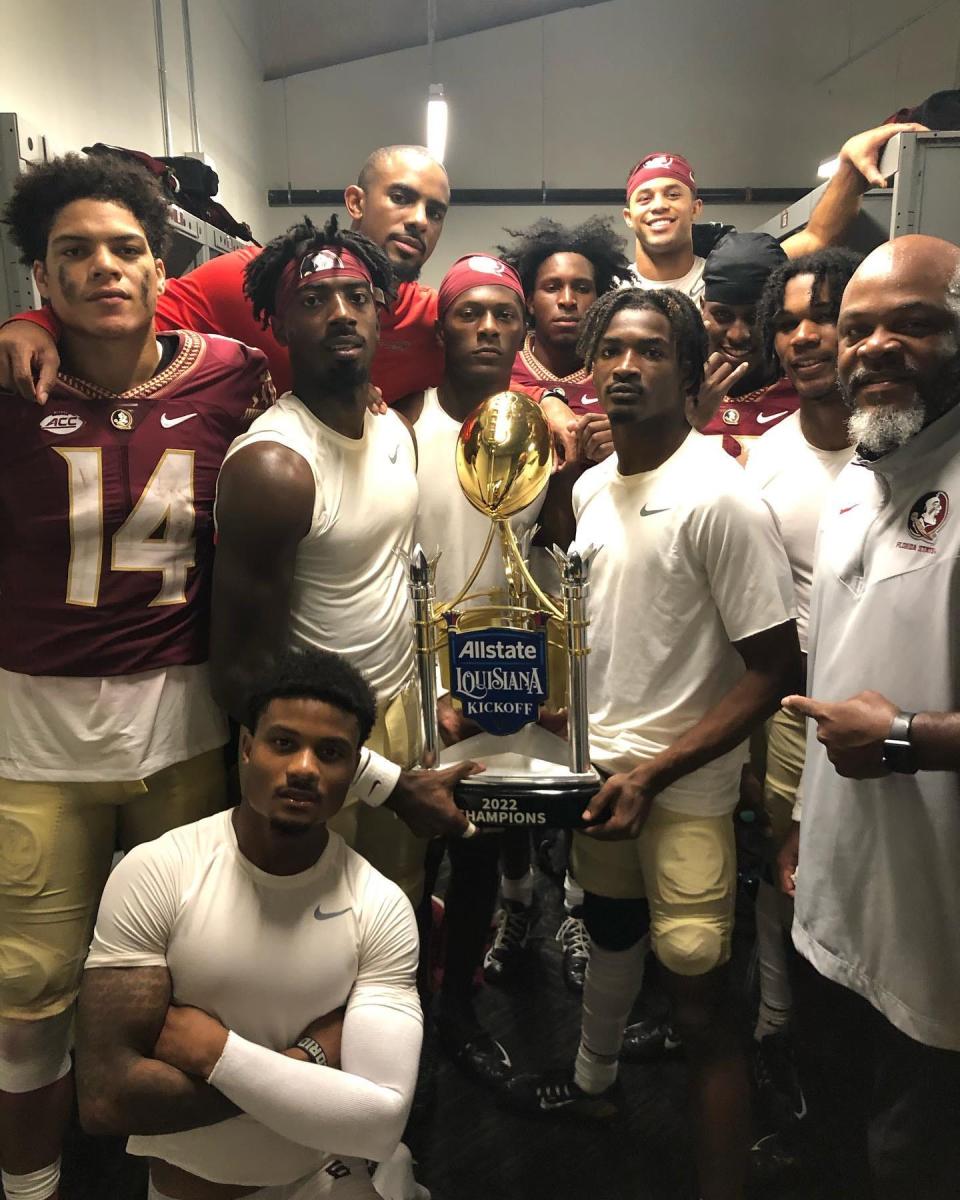 FSU receivers coach Ron Dugans and FSU players pose with the game trophy following the Seminoles' victory over LSU Sunday in New Orleans.