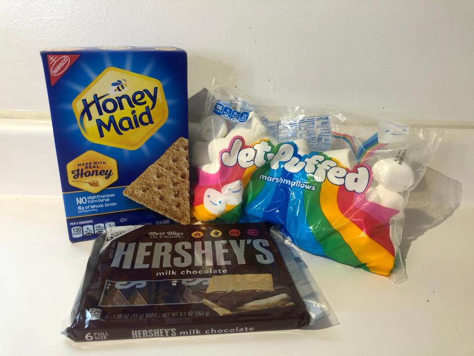 honey maid graham crackers, a package of hershey's chocolate bars and a bag of jet-puffed marshmallows