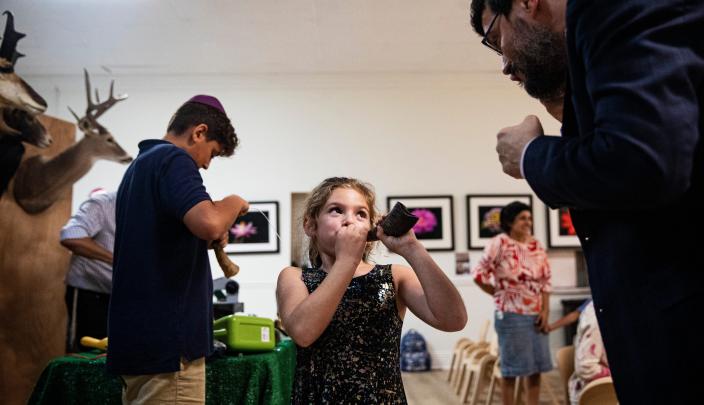 Josie Feintuch, 7, blows into a shofar she helped make during a shofar making class for children at Chabad Naples in Florida on Sept. 14, 2022.